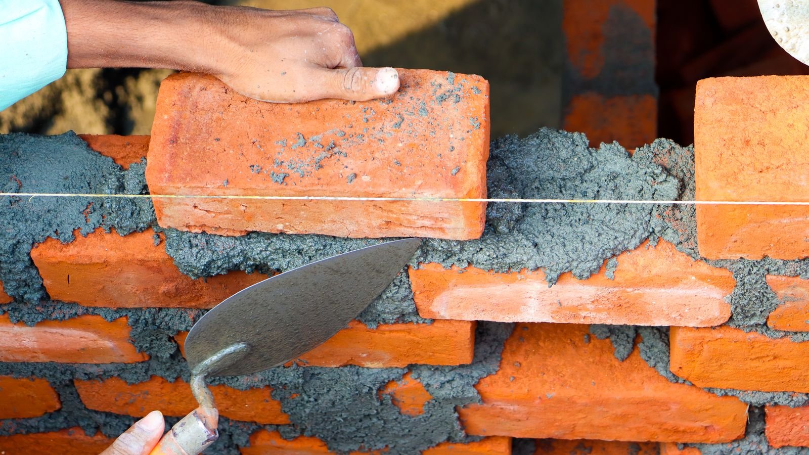 Ouvrier posant des briques avec du mortier sur un chantier