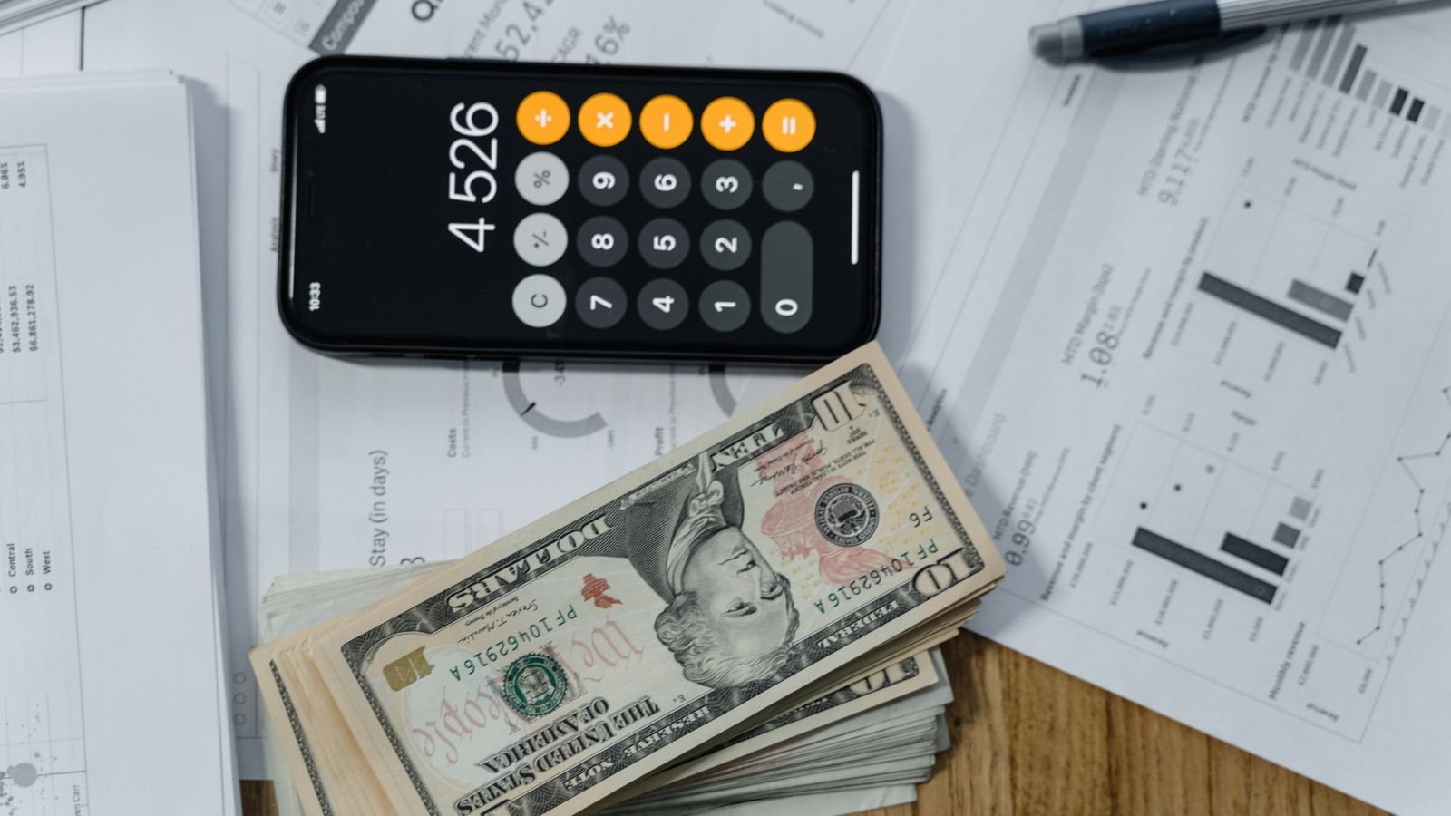 Calculatrice, billets et documents financiers sur un bureau