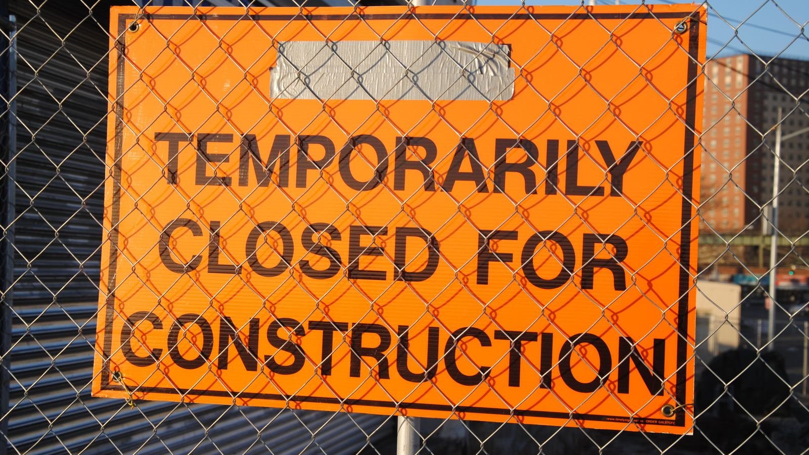 Panneau de chantier orange installé derrière une clôture